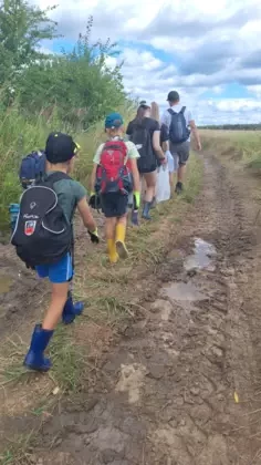 Dzieci i młodzież idą polną drogą.