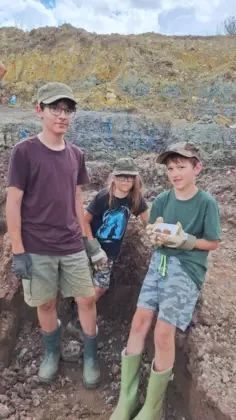 Trzech chłopców pokazuje swoje znaleziska, czyli koprolity.