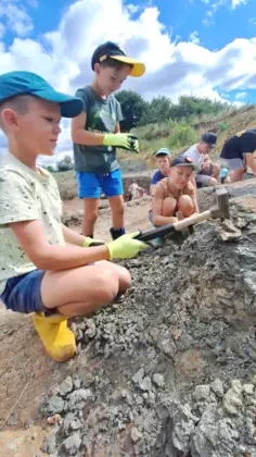 Chłopcy w czapkach, rękawiczkach i kaloszach zaczęli kopać młotkami.