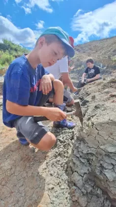 Chłopiec trzyma młotek geologiczny.