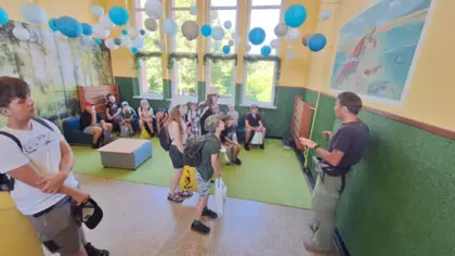 Uczestnicy wyprawy słuchają profesora siedząc na pufach.