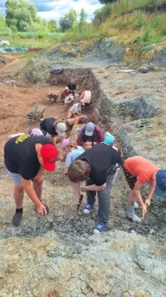 Pochyleni nad ziemią chłopcy szukają skamieniałości.