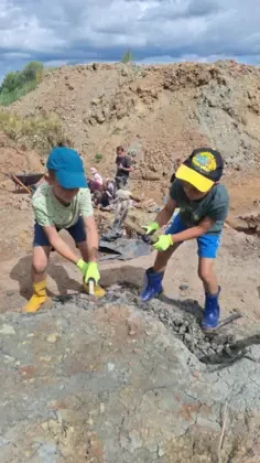 Dwóch chłopców z zaangażowaniem kopie młotkami w ziemi.