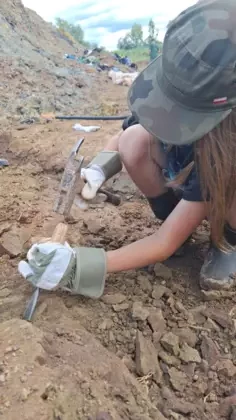 Chłopiec w czapce z dłutem i młotkiem rozkopuje ziemię.