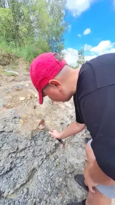 Starszy chłopak w czerwonej czapce rozkrusza gliniane podłoże.