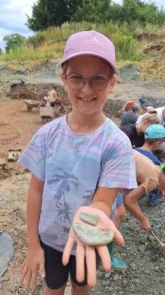 Dziewczynka pokazuje swoje znalezisko, czyli skamieniałą norę zwierzęcia.