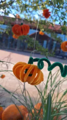 Na zdjęciu widać małe ozdoby  w kształcie dyń, które wiszą na małym drzewie. W tle widać sklep z pamiątkami.