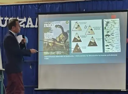 Prof. Tomasz Sulej podczas prelekcji – z pomocą wskaźnika pokazuje uczniom informacje wyświetlane na ekranie.