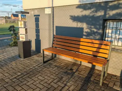 Pod ścianą stoi ławka i pionowa zabawka z ruchomymi elementami.